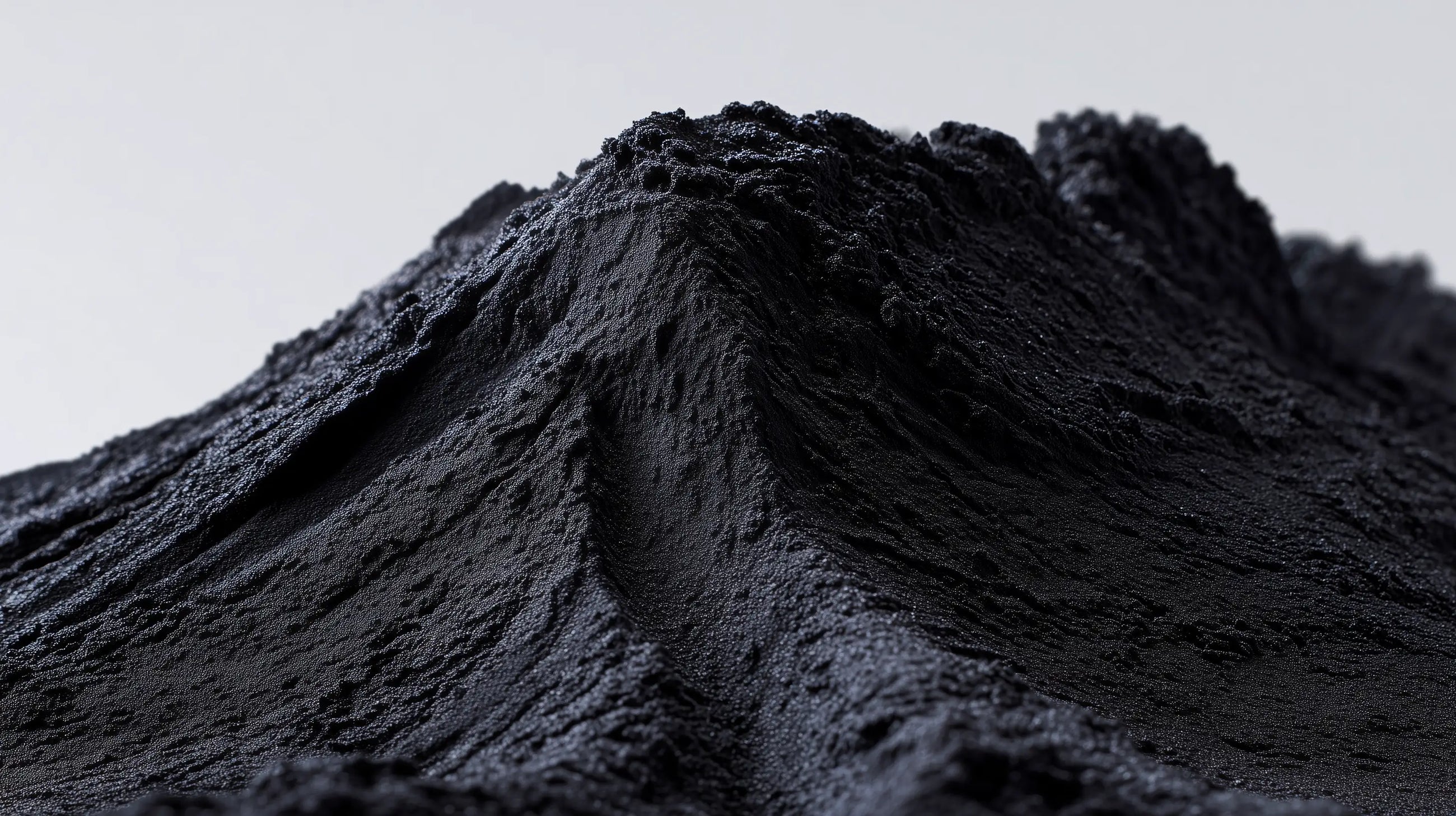 Mound of fine black charcoal mineral powder, natural pigment ingredient in DEFINE mascara