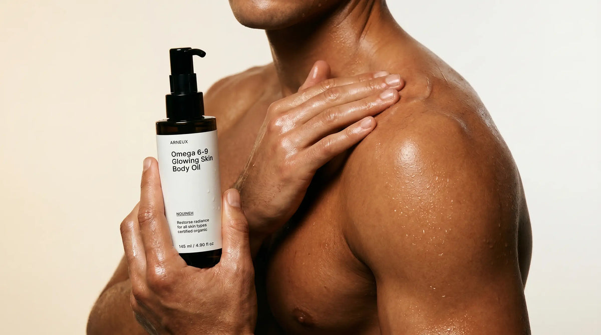 Man stepping out of a shower, damp skin, applying body oil, warm bathroom light