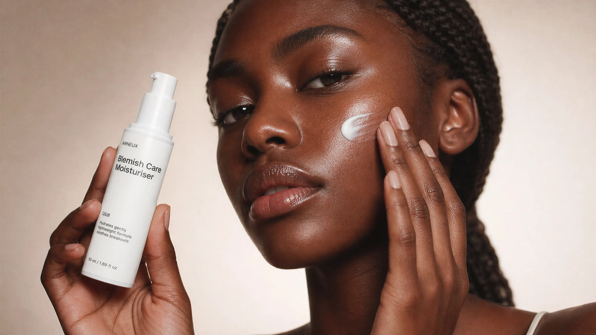 Woman applying ARNEUX skincare product to her face with a beige background