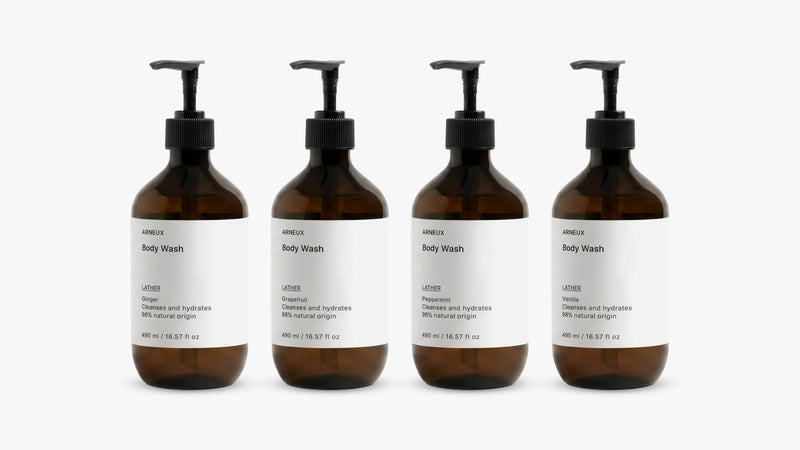 INDULGE The Shower Edit by ARNEUX, four organic body wash scents in amber bottles on white background