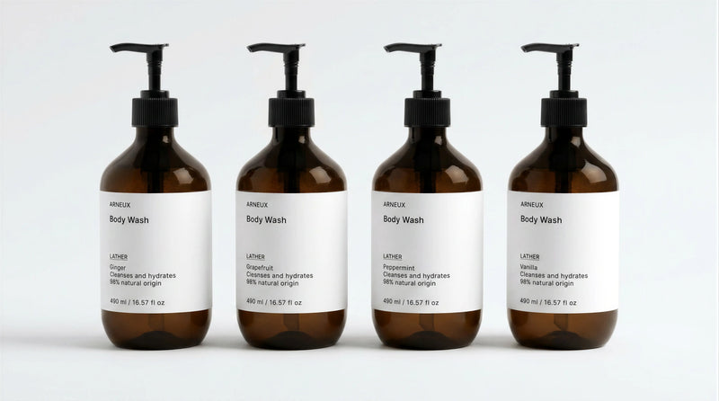 INDULGE The Shower Edit by ARNEUX, four organic body wash scents in amber bottles on white background
