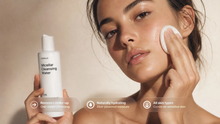 Woman pressing cotton pad to cheek using BARE micellar cleansing water, naturally dewy skin