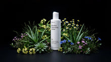 BARE micellar cleansing water bottle nestled in aloe and wildflowers on black background