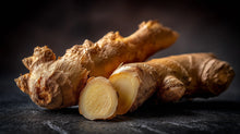 Sliced fresh ginger root on dark surface, anti-inflammatory botanical in blemish care moisturizer