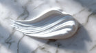 Lightweight blemish care moisturizer cream texture swatch on white marble, silky consistency