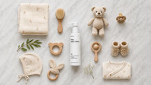 CARE baby body lotion flatlay with teddy bear, wooden toys, swaddle blanket and booties on white marble