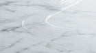A close-up of a clear ARNEUX natural deodorant swipe on a white and gray marble surface
