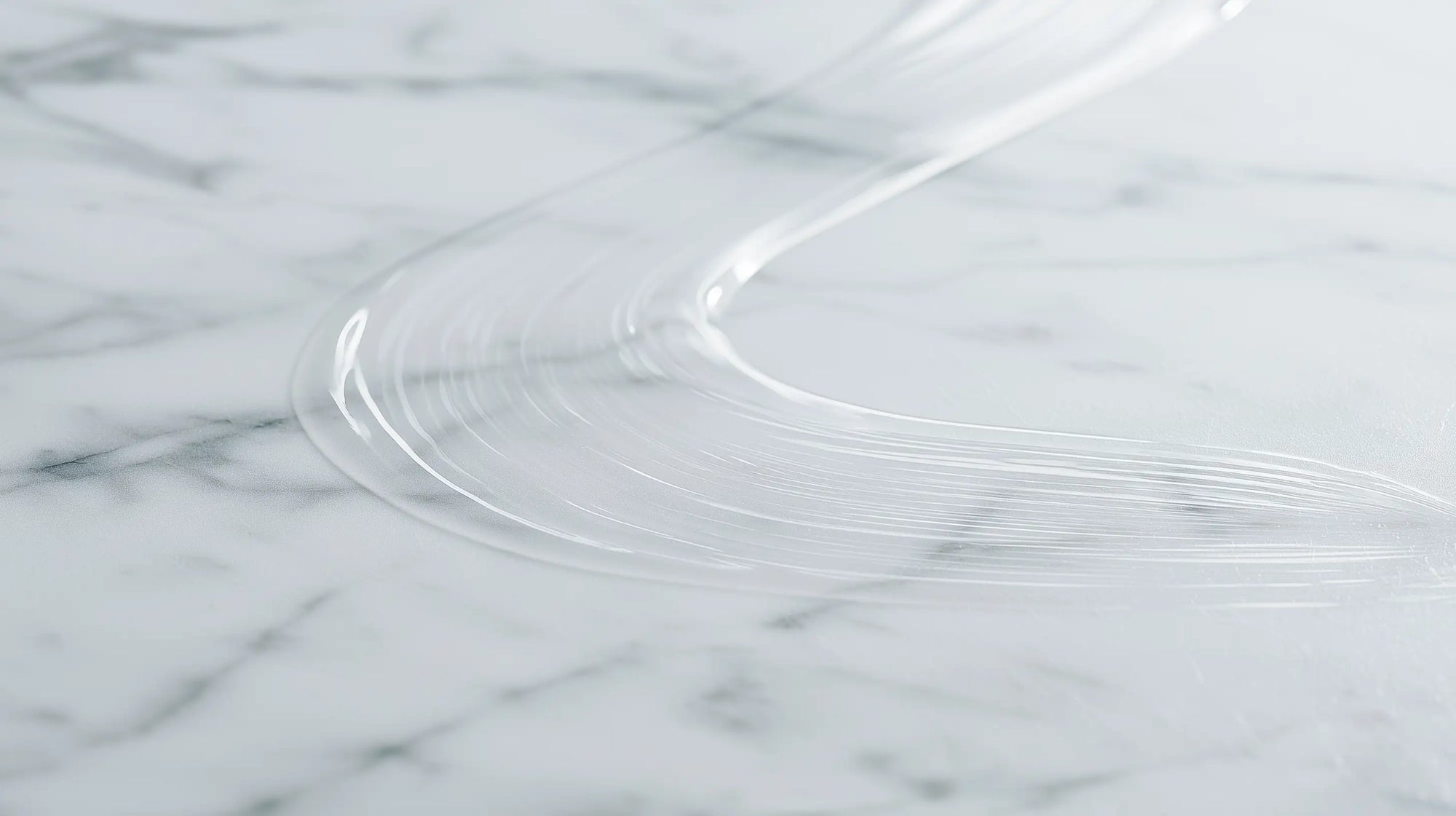 A close-up of a clear ARNEUX natural deodorant swipe on a white and gray marble surface