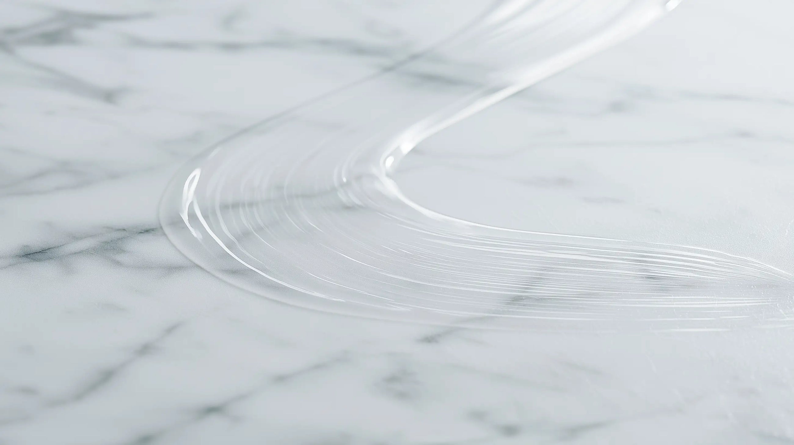 A close-up of a clear ARNEUX natural deodorant swipe on a white and gray marble surface