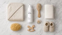 CLOUD foaming baby wash flatlay with hooded towel, hairbrush, washcloth and wooden baby toys on marble