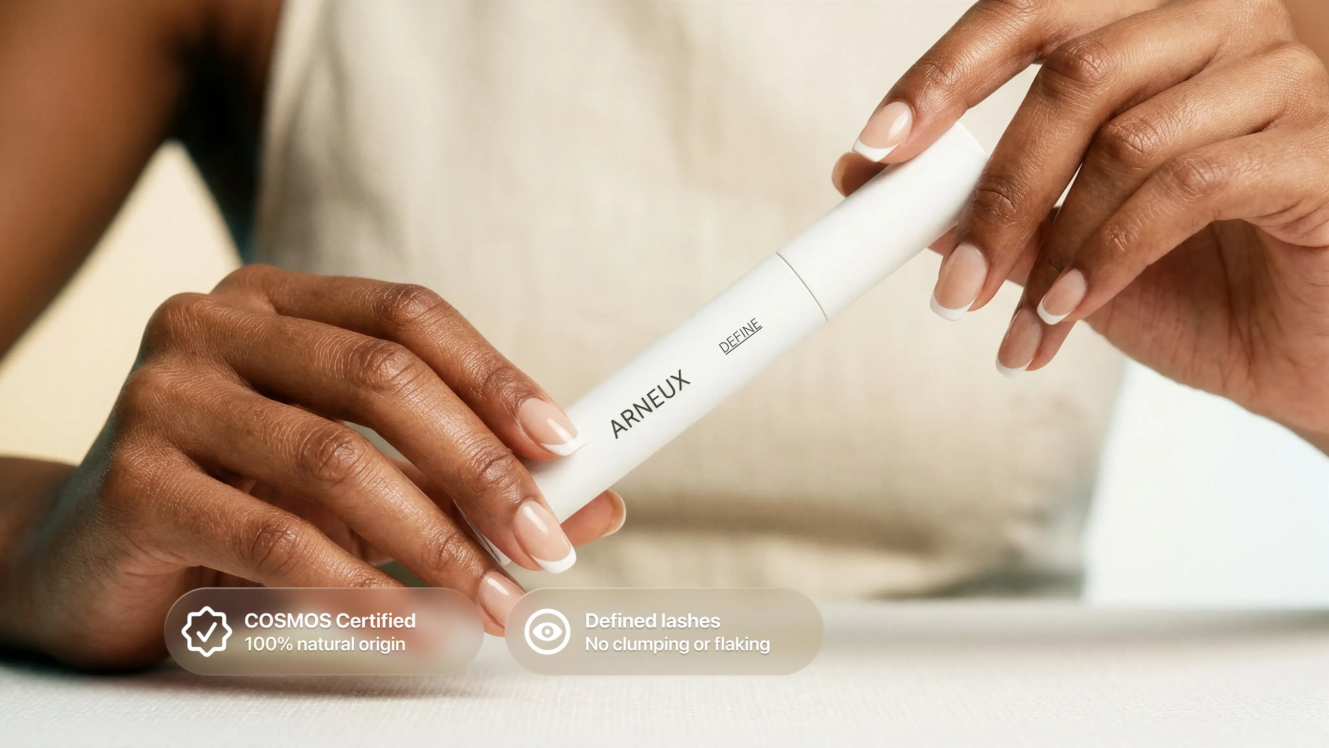 Hand holding DEFINE mascara tube, COSMOS certified 100% natural origin defined lashes callout