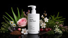 DELICATE baby wash bottle with aloe vera, pink rose, chamomile, white blossoms and cherries on black background
