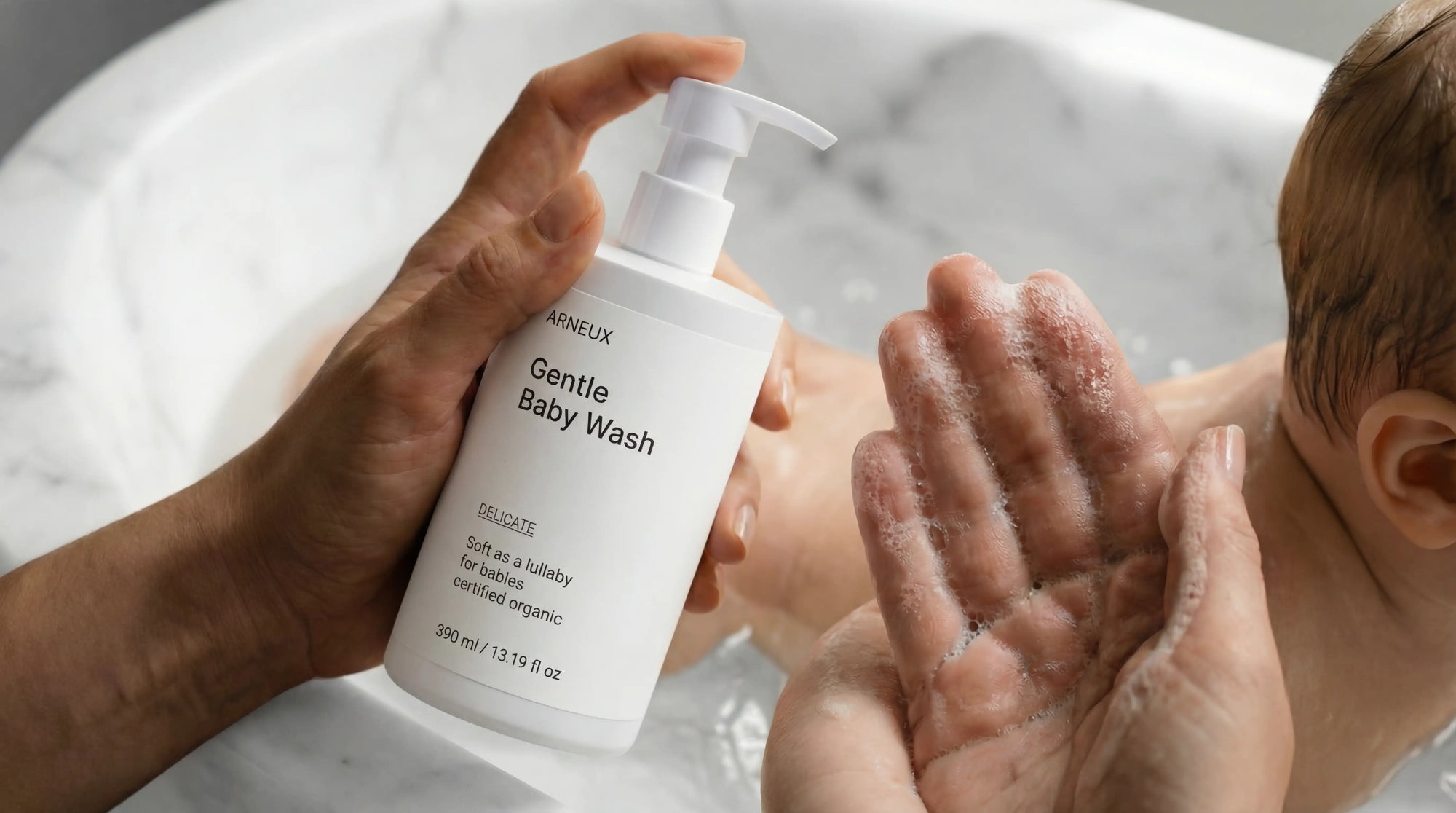 Adult hands lathering DELICATE gentle baby wash in bath, allergen label free COSMOS certified newborns and up