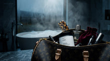 EMBER travel candle packed in luxury travel bag with Arneux products, steamy bathroom in background