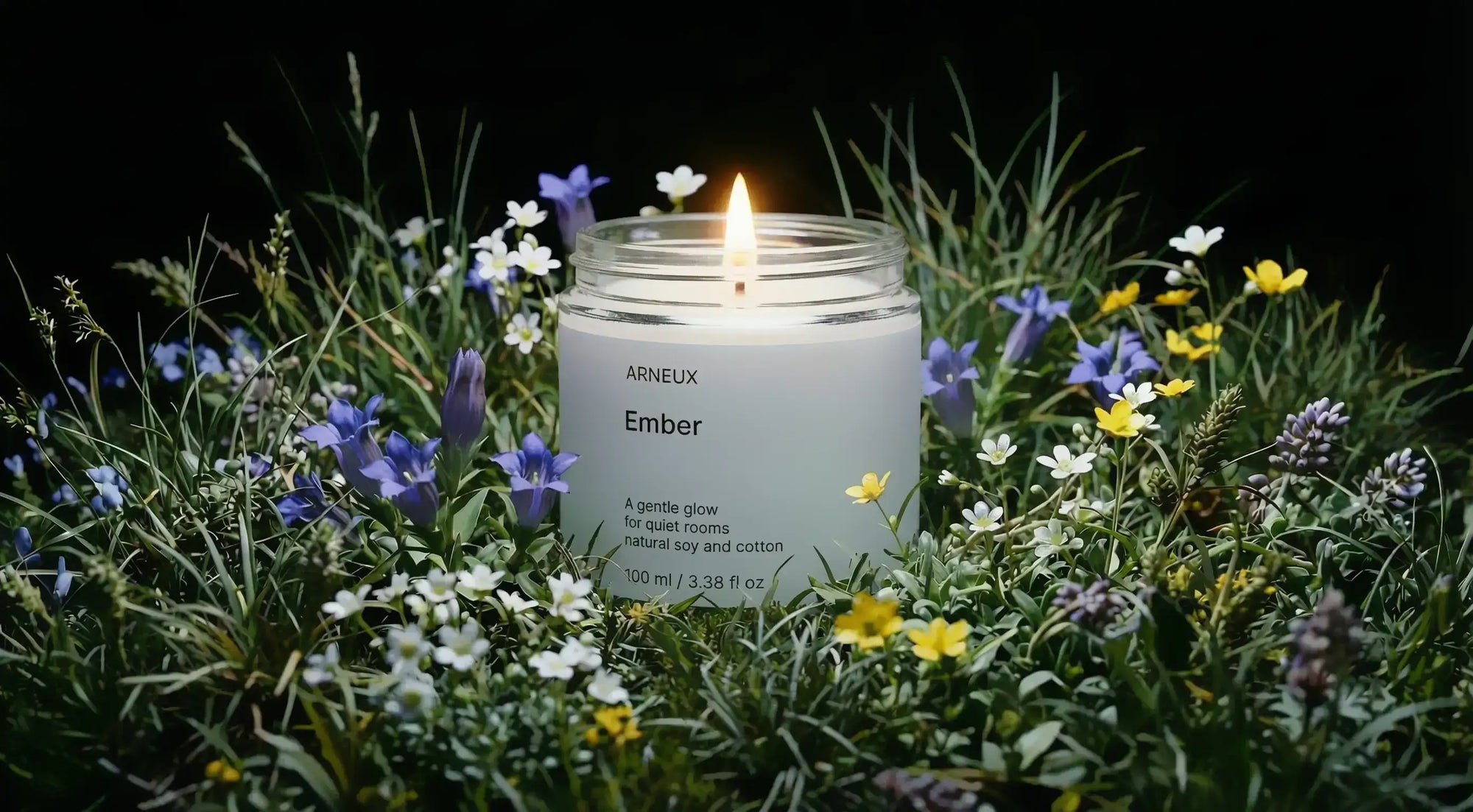 EMBER travel candle burning in wild meadow surrounded by purple white and yellow wildflowers at dusk