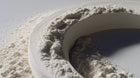 White kaolin clay powder heaped in a bowl close-up, oil-absorbing mineral in FLAWLESS clay mask
