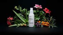 GLOW serum bottle with pink flowers, sea buckthorn, rosehips and purple berries on black background