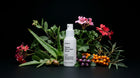GLOW serum bottle with pink flowers, sea buckthorn, rosehips and purple berries on black background