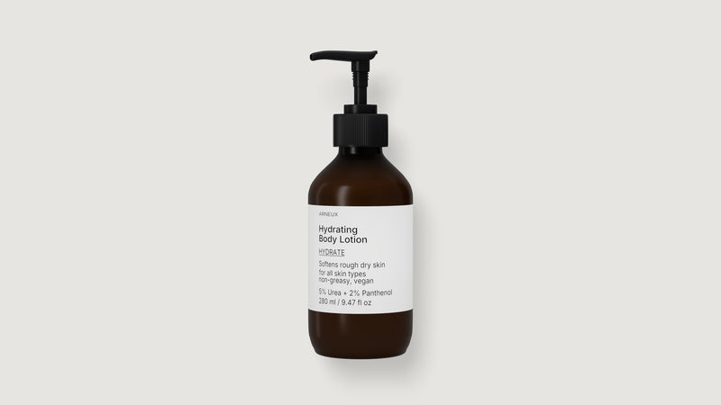 An amber glass pump bottle of ARNEUX hydrating body lotion with a black dispenser and a white label, centered on a light gray background