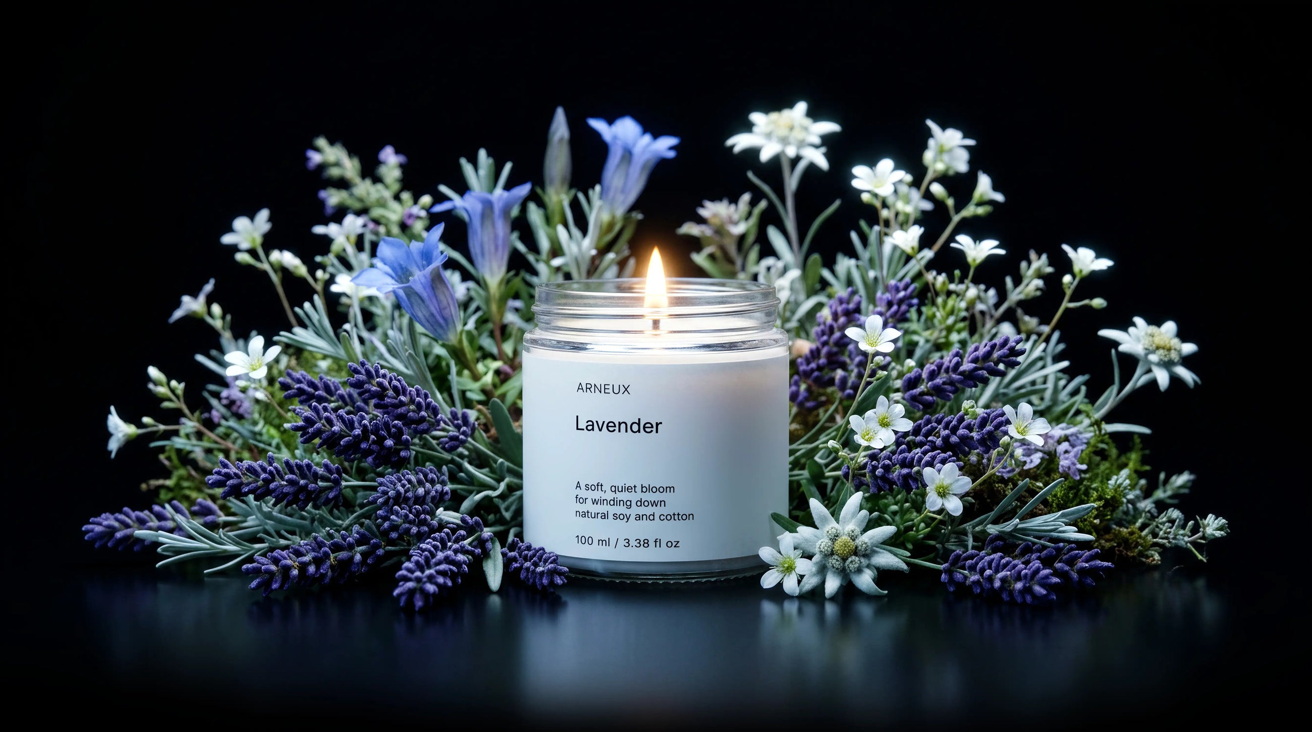 A lit candle labeled ARNEUX Lavender centered among lavender sprigs, white flowers, and blue blossoms on a black background