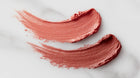 Dusty rose matte lipstick color swatch smeared on white marble showing pigment and texture