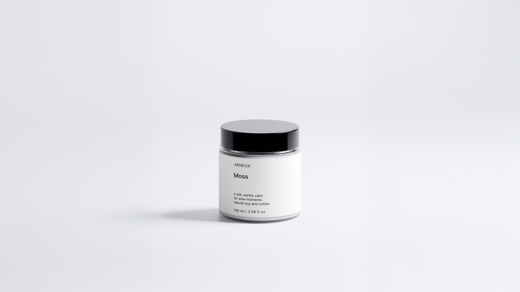 Arneux MOSS travel candle glass jar with black lid, fresh green woody soy wax candle front view on grey background