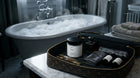 MOSS travel candle in open luxury travel case with Arneux products beside marble vanity and clawfoot bathtub