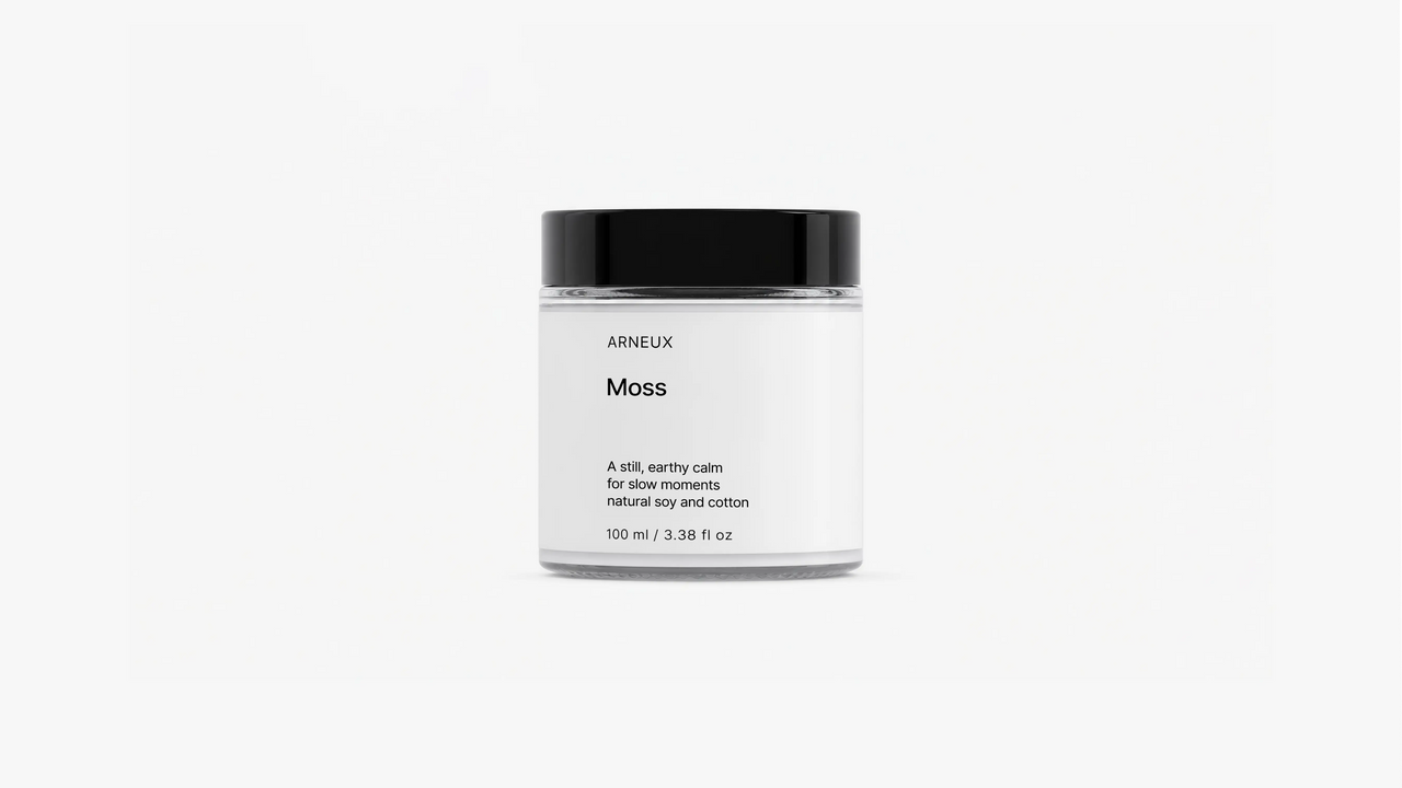 ARNEUX MOSS travel candle glass jar with black lid, fresh green woody soy wax candle front view on grey background