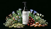 NOURISH body oil bottle surrounded by rosemary, blue florals, rosehips and cardamom on black background