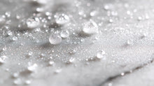 Fine prebiotic face mist droplets scattered on marble surface, weightless hyaluronic mist texture