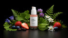 REVIVE serum bottle with strawberries, blueberries, ferns, edelweiss and wildflowers on black