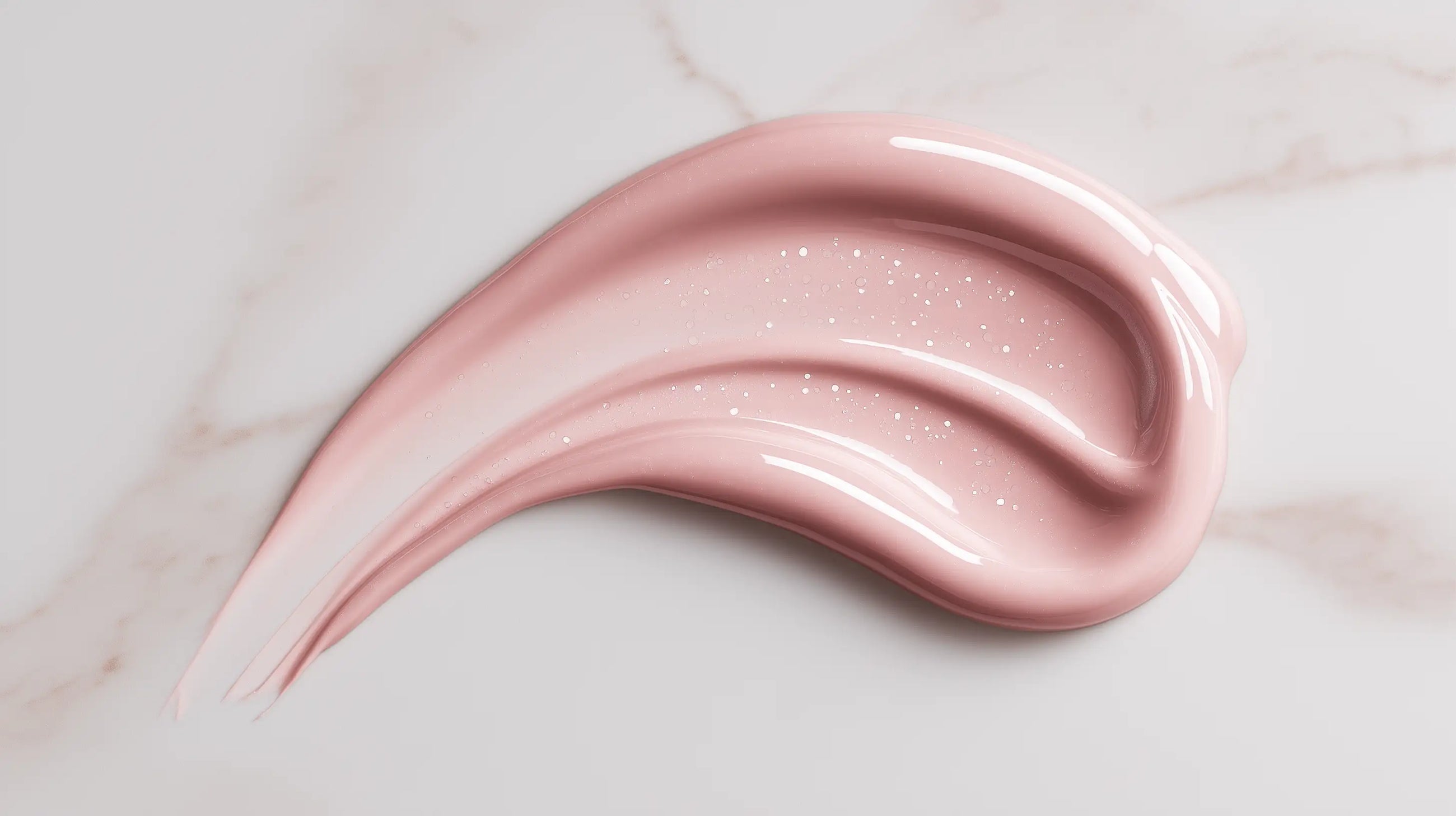 Rose-tinted peptide anti-aging serum swatch on white marble showing lightweight glossy texture