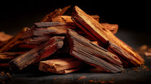 Stacked sandalwood wood sticks on dark surface, conditioning aromatic ingredient in ROOT rosemary hair oil