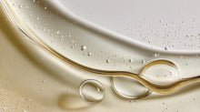 Golden rosemary hair oil swirling on surface with fine droplets, lightweight concentrated formula texture