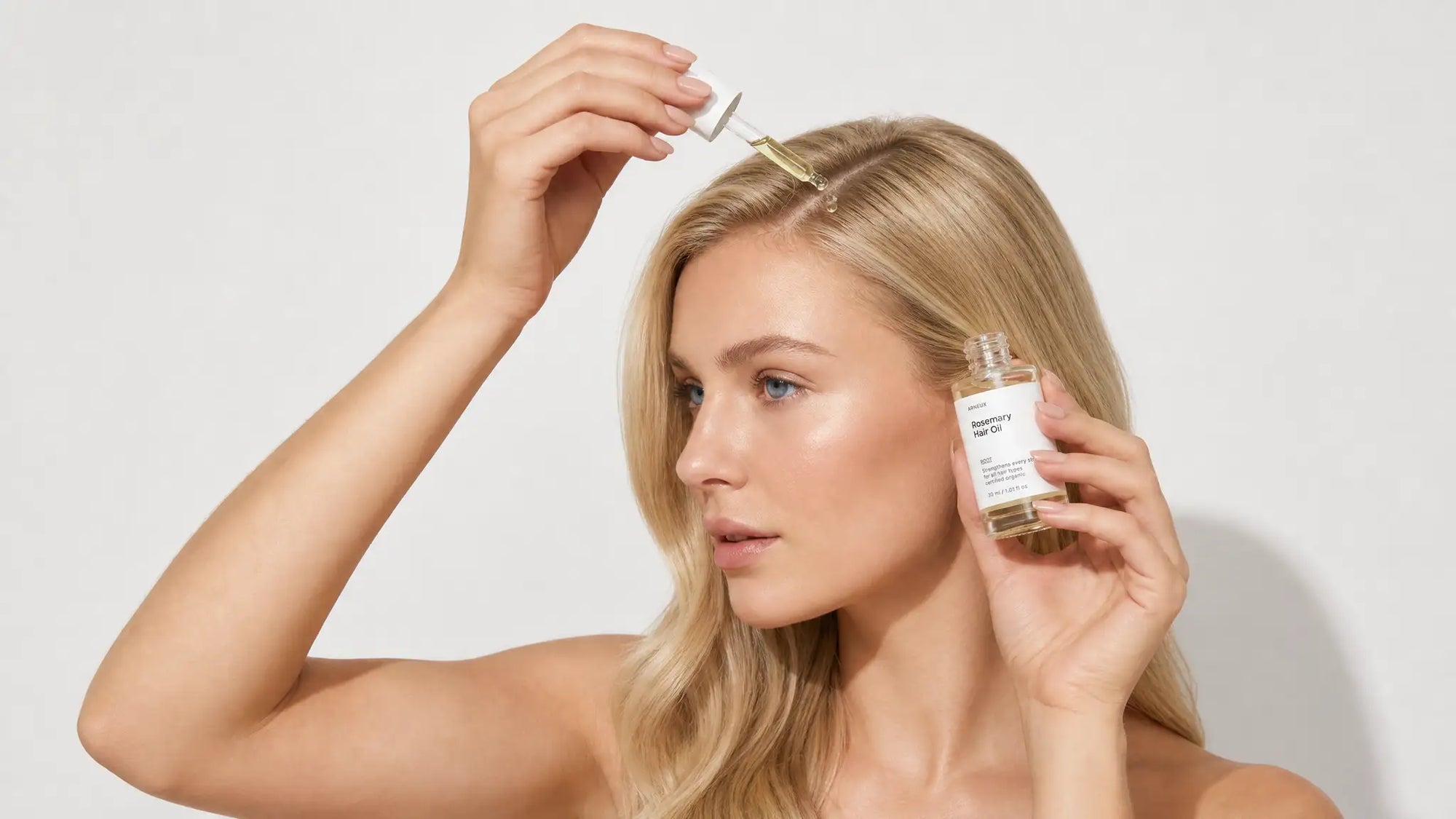 Woman applying Arneux ROOT rosemary hair oil dropper to scalp, 7AM hair ritual no silicones no sulfates