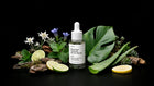 SHIELD serum bottle with edelweiss, monstera leaf, aloe vera, lime and bark on black background