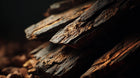 Dark textured bark pieces close-up, natural prebiotic extract ingredient in SHIELD barrier serum
