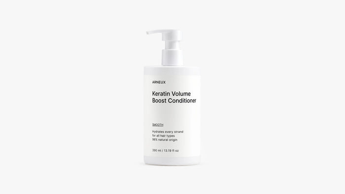 A white pump bottle of Arneux Keratin Volume Boost Conditioner, photographed against a seamless light gray studio background