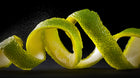 Curled lime peel on dark background, brightening citrus botanical in keratin volume boost conditioner