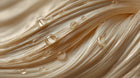 Golden keratin hair strands with oil droplets close-up, showing smooth repaired hair texture