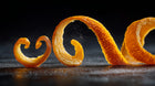 Curled fresh orange peel strips close-up, brightening citrus botanical in keratin leave-in hair mist