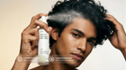 Man spraying TAME keratin leave-in mist into curly hair, COSMOS certified leave-in treatment callout