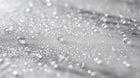 Fine keratin hair mist spray droplets scattered on silver surface, weightless mist formula texture