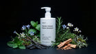 WASH shampoo bottle with mint, rosemary, blue flowers, vanilla pods and cinnamon on black background