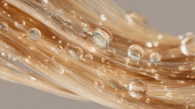 Golden hair strands with water droplets close-up, showing smooth keratin-strengthened hair texture