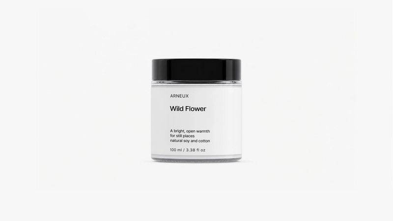 ARNEUX Wild Flower travel candle glass jar with black lid, light floral soy wax candle front view on grey background