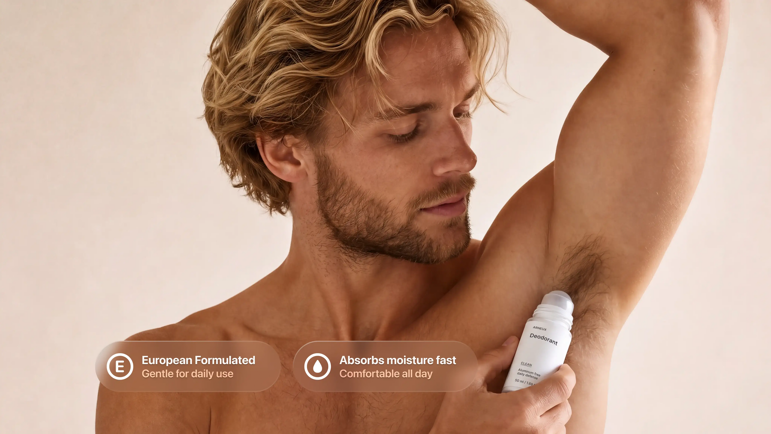 A man with blonde hair and a beard applies ARNEUX CLEAN deodorant to his underarm, shown against a warm beige background