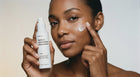Woman pressing RENEW retinol alternative moisturizer into cheek with fingertips, smooth firm skin