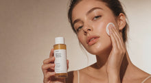 Woman sweeping cotton pad along cheekbone with DISSOLVE biphasic remover, close skin texture view