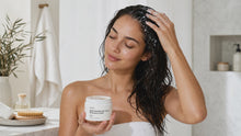Woman working RESET rosemary mint hair scrub through wet hair at sink, scalp exfoliation routine